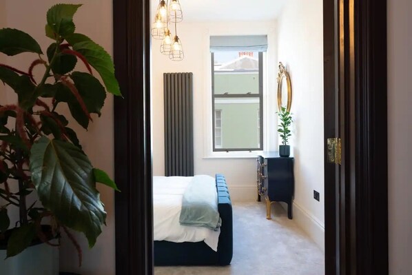 A bedroom with a bed, a window, a radiator, and a plant. - Lookout by the Bay (Herne Bay)