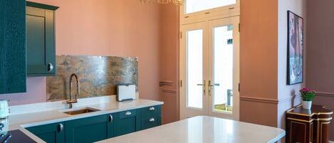 A modern kitchen with teal cabinetry, a large island, and pendant lighting.
