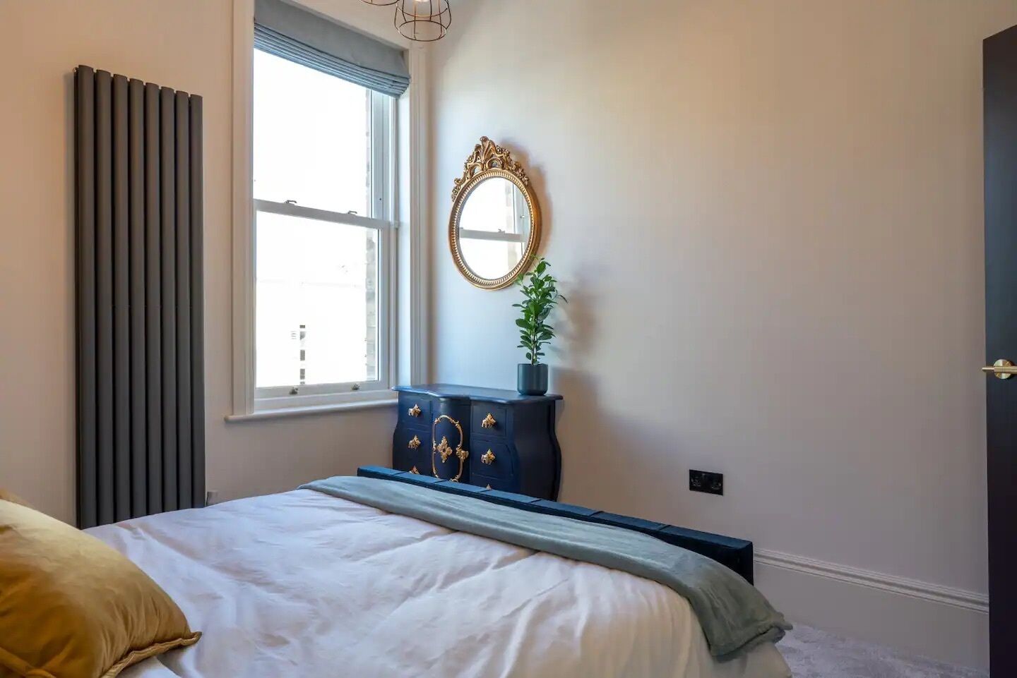 Une chambre à coucher avec un lit, une commode, un miroir et une fenêtre.