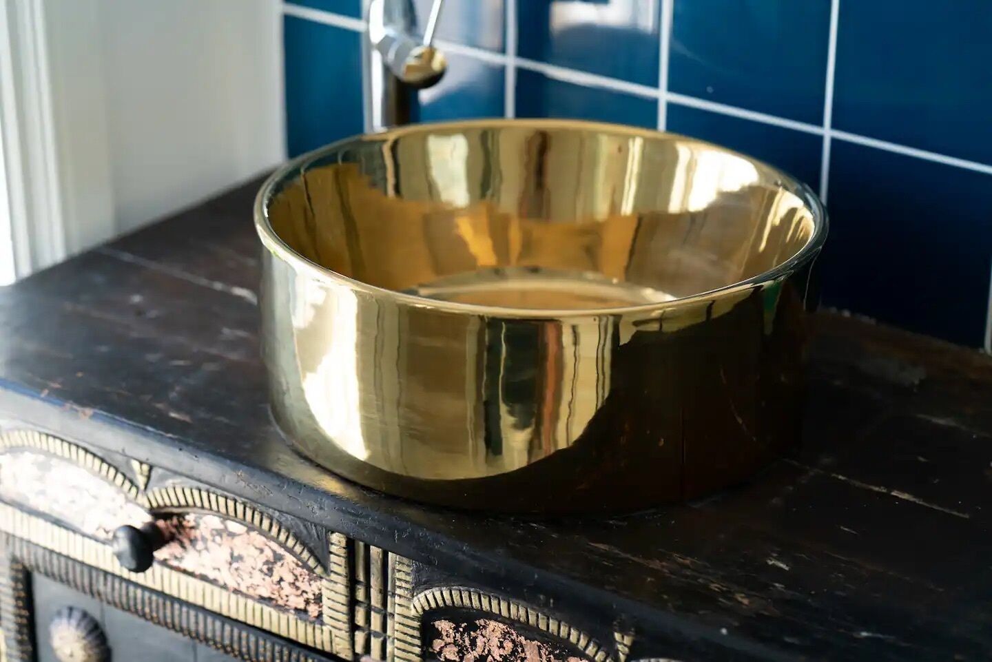 A shiny, empty brass bowl on a dark surface with intricate designs.
