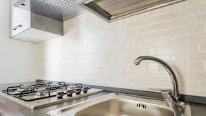 A modern kitchen with a gas stove, stainless steel sink, and white tiled backsplash. - Chez Isabella by Wonderful Italy (Noicattaro)