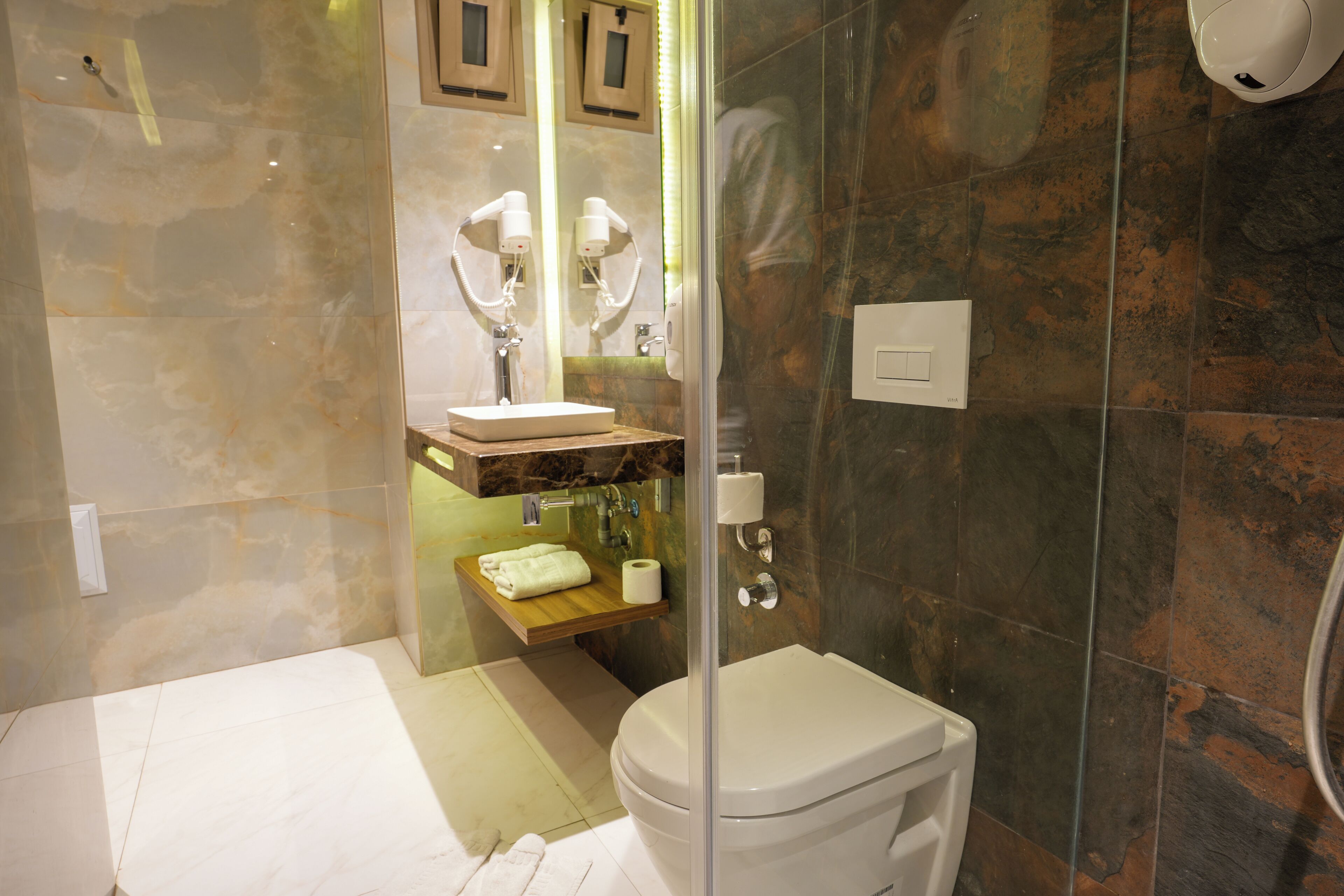 A modern bathroom with a glass-enclosed shower, a white toilet, a marble vanity, and a towel rack.