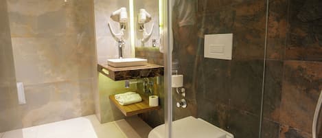 A modern bathroom with a glass-enclosed shower, a white toilet, a marble vanity, and a towel rack.