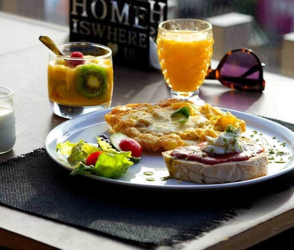 A breakfast setting with a plate of food, a glass of orange juice, and a book titled "HOME IS WHERE".