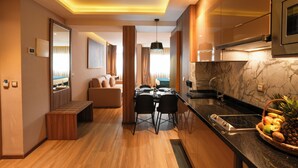 A modern kitchen with a built-in oven, a dining area with a table and chairs, and a seating area with a sofa and a coffee table.
