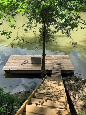 Guests can enjoy a serene lakeside retreat with a dock featuring a bench and a tree for shade.