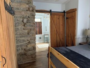 Cozy retreat with a rustic stone wall, wooden bed, and dark wood floor.
