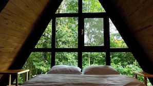 A room with a sloped ceiling and large windows, a bed, and a wooden bench. - Pentalow Cabin (Kartepe)