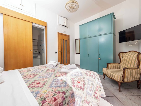 A bedroom with a bed, a wardrobe, a chair, and a television. - Maison Rosa (Meta)