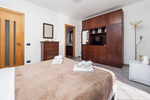 A bedroom with a bed, wooden wardrobe, a mirror, and a white radiator. - Maison Rosa (Meta)