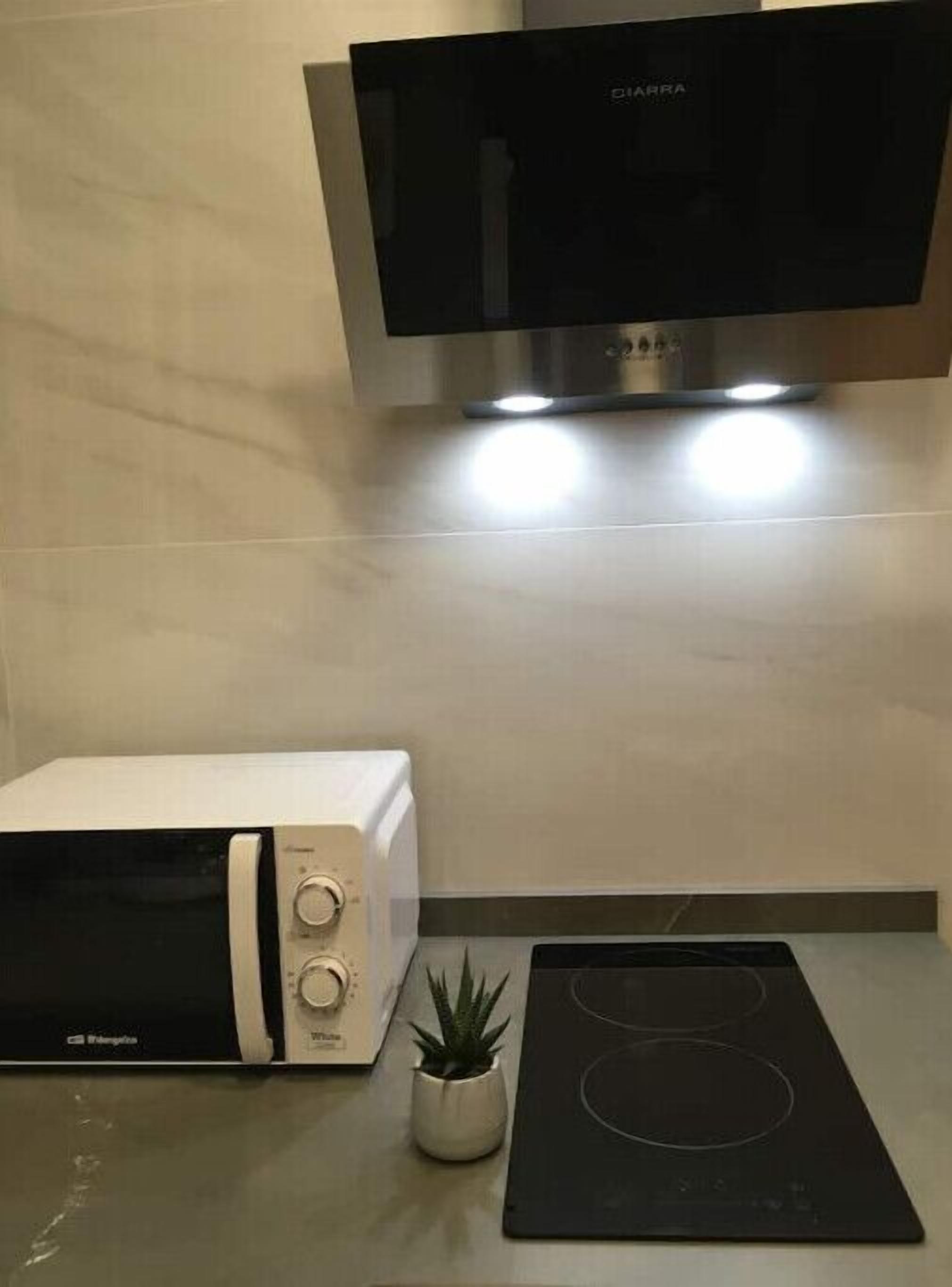 A kitchen with a microwave, a small potted plant, and a black induction cooktop.