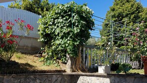 A patio area with stone walls, a white fence, and potted plants.