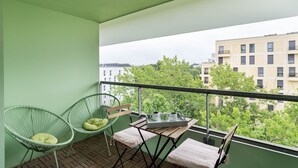 Ein Balkon mit zwei Korbstühlen, einem kleinen Tisch und einer gepolsterten Bank.