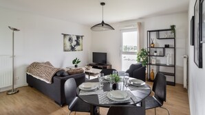 Ein modernes Wohnzimmer mit Essbereich, einer Couch, einem Fernseher und einem Bücherregal.