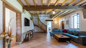 Amplia sala de estar con una escalera de madera, un conjunto de sofás y una mesa de centro.