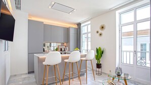 Une cuisine moderne dotée d’un îlot central, de tabourets de bar et d’une table en verre sur laquelle est posé un magazine.