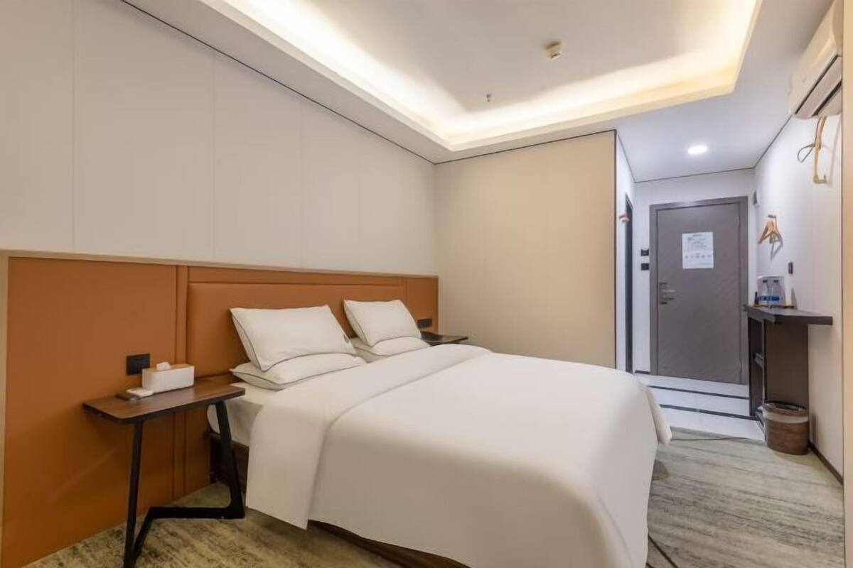 A hotel room with a bed, bedside table, and a door to the bathroom.
