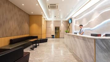 A hotel reception area with a marble floor, a reception desk, and seating area.