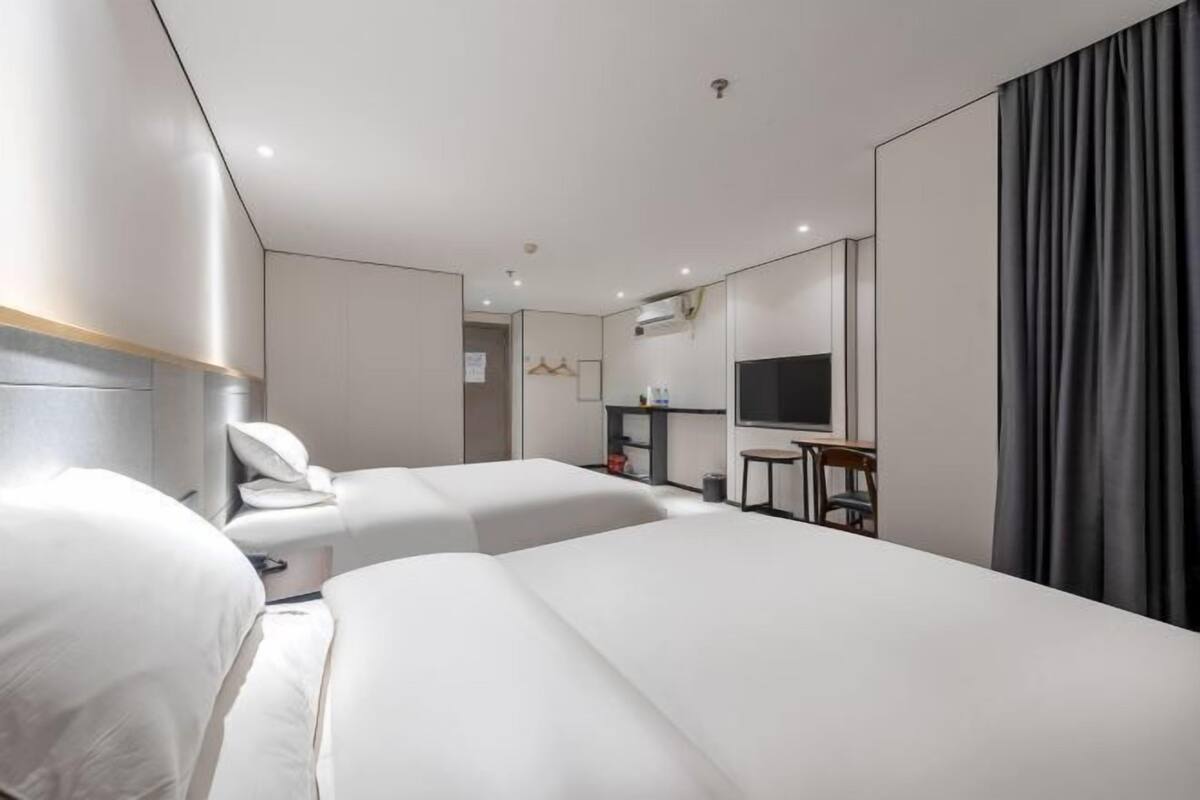 A hotel room with two beds, a TV, a desk, and a wardrobe.