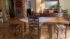 A dining area with a wooden table and chairs, a lace table runner, and a mirror above the table.