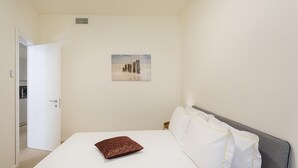 A hotel room with a bed, a pillow, a painting, and a door leading to a bathroom. - Riviera Flavour Apartments by Wonderful Italy - Valeriana (Santa Margherita Ligure)