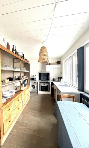 Cocina compacta con lavadora, microondas y una lámpara colgante.