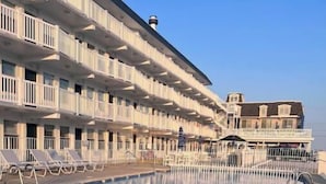 A pool area with a large building in the background. - Sunny Wildwood Crest condo! Perfect spot, 1 block to beach ☀️🌊 (Wildwood)