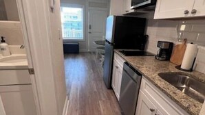 A kitchen with white cabinets, a stainless steel sink, and a microwave. - Sunny Wildwood Crest condo! Perfect spot, 1 block to beach ☀️🌊 (Wildwood)
