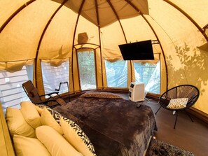 Relax in a cozy tent-style accommodation with a comfortable bed, flat-screen TV, and seating area.