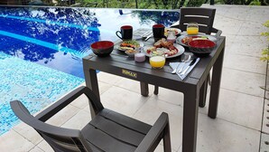 A dining table set with breakfast items and a pool in the background. - Romantic glamping at Vista Hermosa, enjoy nature in a private and cozy environment. (San joaquin-La Mesa)