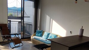 Una sala de estar moderna con un sofá, una mesa de centro, una zona de bar y un balcón con vistas.