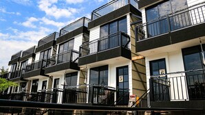 Un edificio residencial de varios pisos con balcones, ventanas amplias y un cielo despejado.