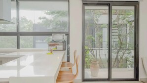 A modern kitchen with a large window, a built-in microwave, and a wooden chair. - Royal PH Private Rooftop Deck Pool (Tulum)