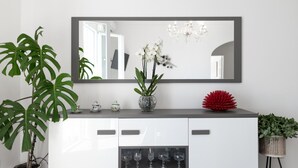 A modern kitchen with a large mirror, a potted plant, and a decorative red object on the counter.