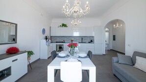 A modern kitchen with white cabinets, a dining table set for four, and a chandelier.