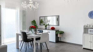 A modern dining area with a white table, black chairs, and a chandelier.