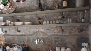 Una cocina rústica con paredes de piedra, armarios de madera y una variedad de utensilios y utensilios de cocina.