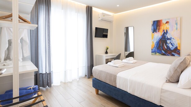 Une chambre d’hôtel moderne équipée d’un lit, d’un bureau, d’une armoire et d’un tableau au mur.