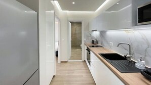 Une cuisine moderne avec des meubles blancs, un plan de travail noir et un four à micro-ondes encastré.