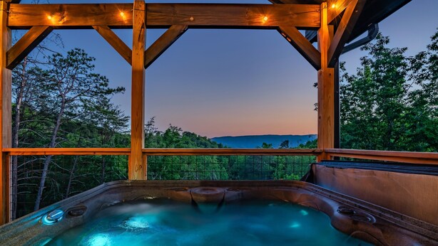 Ein Whirlpool mit Holzterrasse und Blick auf eine bewaldete Landschaft.