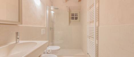 A compact bathroom with a sink, toilet, and shower.