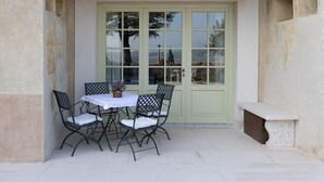 A patio with a table and chairs, a bench, and a door with glass panels.