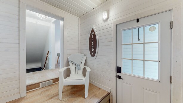 A room with a white door, a window with blinds, a white chair, and a welcome sign on the wall. - The Playmakers Funhouse: HOF Village (Canton)