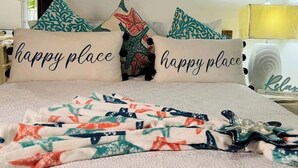 A bedroom with a bed, decorative pillows, a wall art piece, and a bedside table with a lamp. - 1 bedroom Beach House at Bluefields Bay (bluefields)