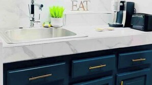 A kitchen with dark blue cabinets and gold handles, a white countertop, a sink, a coffee maker, and a potted plant. - 1 bedroom Beach House at Bluefields Bay (bluefields)