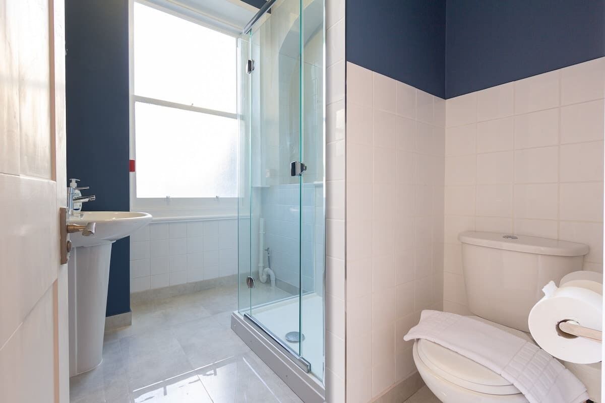Une salle de bain avec une douche à parois de verre, des toilettes et un lavabo.