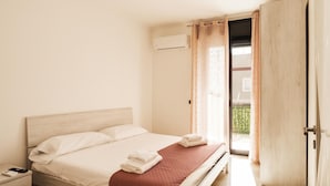 A bedroom with a bed, a nightstand, an air conditioning unit, and a door leading to an outdoor area. - Casa Lungomare IX Maggio (Bari)
