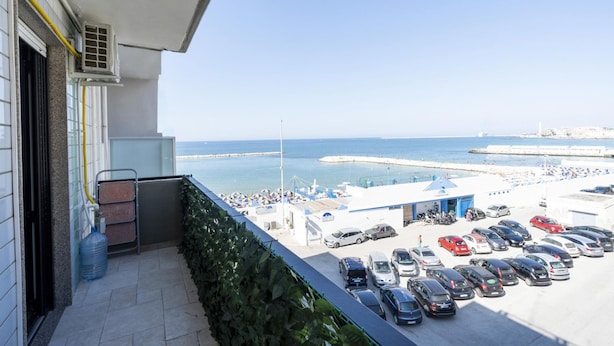 A balcony with a view of a parking lot and the sea. - Casa Lungomare IX Maggio (Bari)