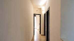 A narrow hallway with a door at the end leading to a bright room. - Casa Lungomare IX Maggio (Bari)