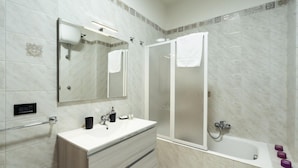 A modern bathroom with a vanity, mirror, shower, and bathtub. - Casa Lungomare IX Maggio (Bari)